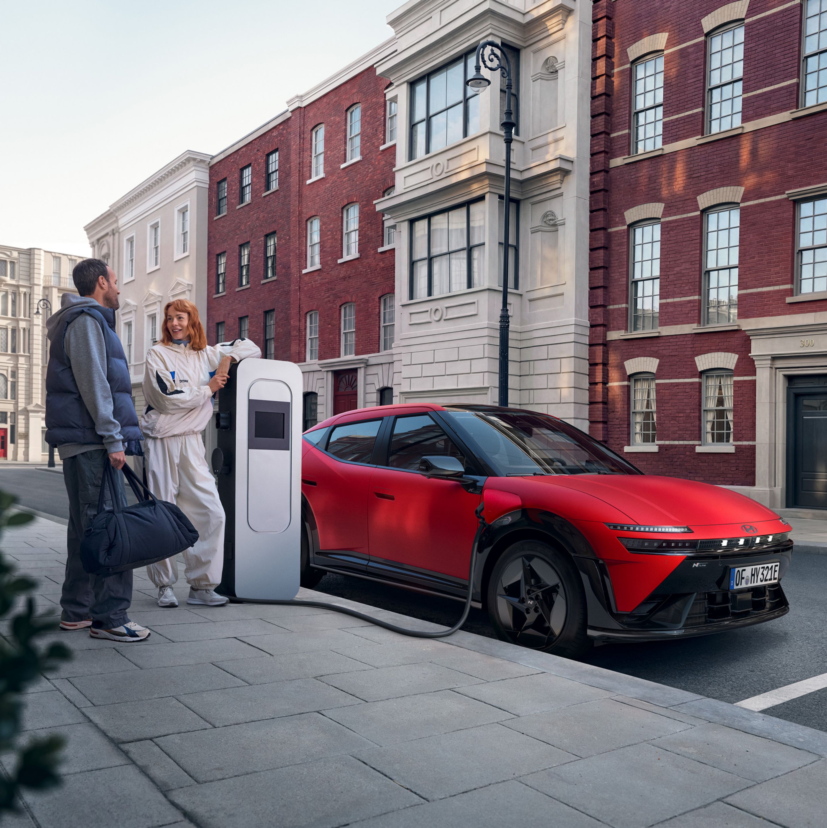 Hyundai IONIQ 3 charging on a city street with two people standing nearby.